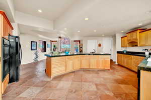Kitchen featuring recessed lighting, ceiling fan, black appliances, a kitchen island with sink, and light brown cabinets