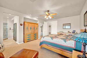 Bedroom featuring light carpet, a ceiling fan, and ensuite bath