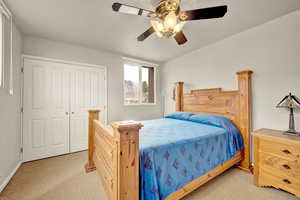 Bedroom with light carpet, ceiling fan, and a closet