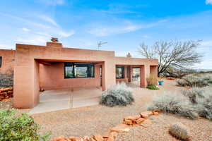 Rear view of house with stucco siding, a chimney, and a patio