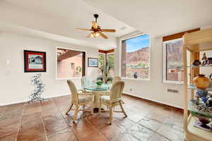 Dining space with stone tile floors, a mountain view, and ceiling fan