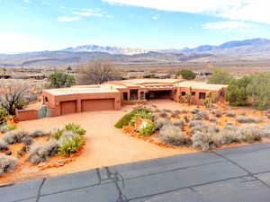 View of front of home with a mountain view, dirt driveway, stucco siding, and a garage
