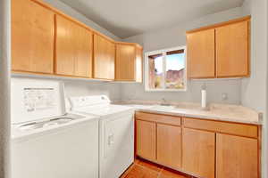 Washroom featuring washer and clothes dryer, light tile patterned floors, and cabinet space