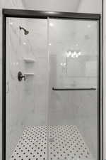 Full bath featuring a marble finish shower