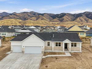 View of front of house featuring covered porch, stone siding, a residential view, concrete driveway, and a mountain view