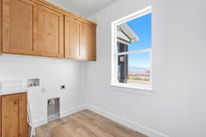 Laundry area featuring hookup for a washing machine, a mountain view, light wood finished floors, electric dryer hookup, and cabinet space