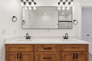 Full bath featuring double vanity and a marble finish shower