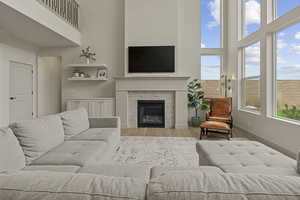 Living room featuring a glass covered fireplace, wood finished floors, and a towering ceiling