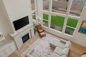 Living area featuring a high ceiling, light wood finished floors, and a high end fireplace