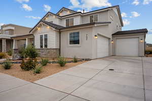 View of front of property featuring driveway, stucco siding, a tiled roof, and stone siding