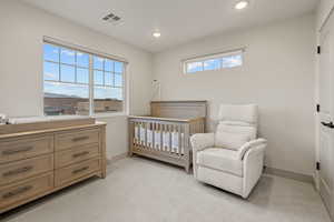 Bedroom featuring light carpet, a nursery area, and recessed lighting