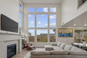 Living area with wood finished floors, a high ceiling, and a fireplace
