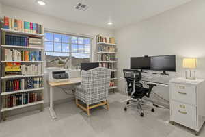 Office space with light colored carpet and recessed lighting