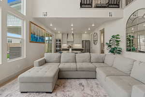 Living room with a high ceiling, recessed lighting, and wood finished floors