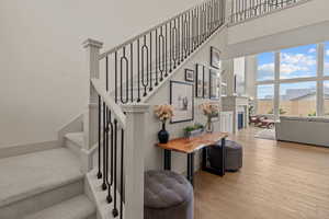 Stairway with wood finished floors, a towering ceiling, and a glass covered fireplace