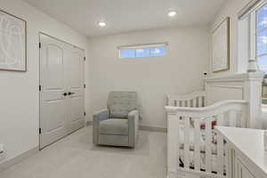 Bedroom featuring light colored carpet, a crib, recessed lighting, and a closet