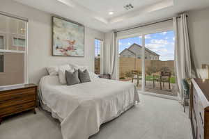 Carpeted bedroom featuring access to exterior, a tray ceiling, and recessed lighting
