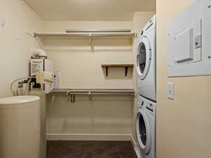 Laundry area featuring electric panel, stacked washer / drying machine, and a textured ceiling