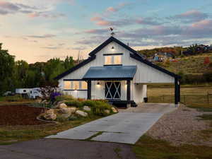 Modern farmhouse with board and batten siding, an attached carport, driveway, a metal roof, and covered porch