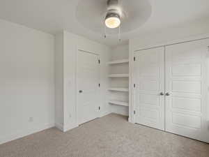Unfurnished bedroom featuring light colored carpet, a closet, and a ceiling fan