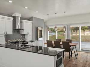 Kitchen with dark stone countertops, decorative light fixtures, white cabinetry, a peninsula, and lofted ceiling