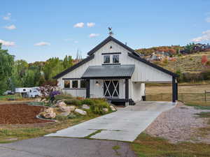 Modern farmhouse with board and batten siding, concrete driveway, a carport, and a metal roof