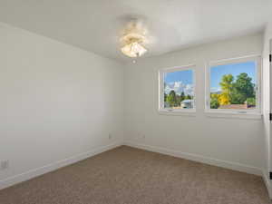 Carpeted empty room with baseboards and a ceiling fan