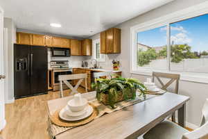 Kitchen with black appliances, light countertops, brown cabinetry, light wood-type flooring, and a textured ceiling