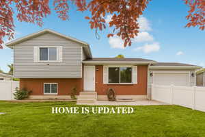 Split level home with an attached garage, entry steps, and roof with shingles