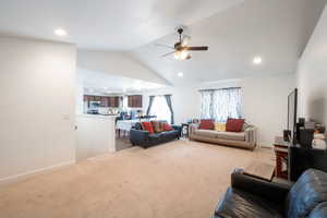Living room with lofted ceiling, light carpet, ceiling fan, and recessed lighting