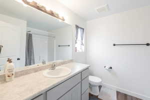 Bathroom with vanity, a shower with shower curtain, and dark wood finished floors