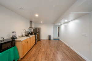 Kitchen featuring light countertops, stainless steel electric stove, black microwave, extractor fan, and wood finish floors