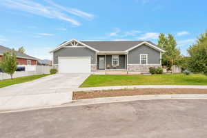 View of front of property with stone siding, covered porch, driveway, and an attached garage