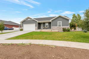 Ranch-style home with stone siding, covered porch, concrete driveway, and a garage