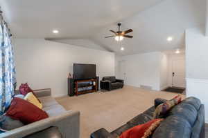 Living room with vaulted ceiling, carpet, a ceiling fan, and recessed lighting