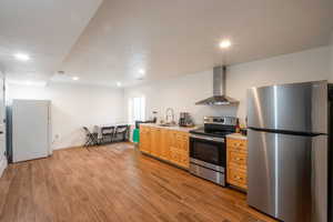 Kitchen featuring appliances with stainless steel finishes, wall chimney exhaust hood, light countertops, dark wood-style floors, and recessed lighting