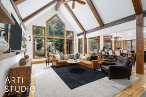 Living area with high vaulted ceiling, beam ceiling, a chandelier, light wood-style floors, and a ceiling fan