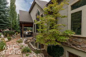 View of side of property featuring roof with shingles, a patio, and stucco siding