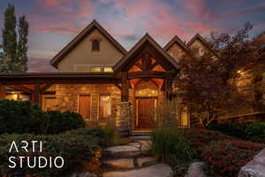 View of front of property featuring stone siding, covered porch, and stucco siding