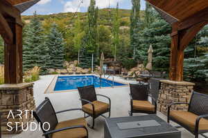 Outdoor pool featuring a patio area, an outdoor living space, and a view of trees