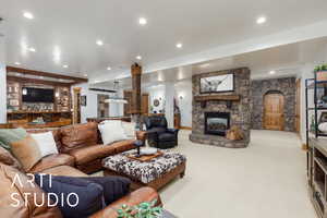 Carpeted living room with a stone fireplace and recessed lighting