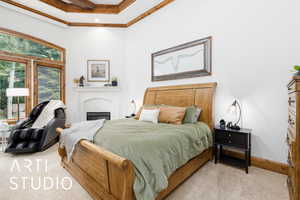 Bedroom featuring light carpet, a glass covered fireplace, and crown molding