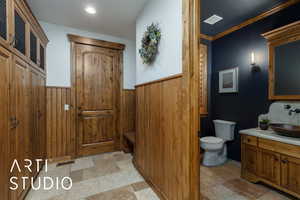Bathroom featuring vanity, stone tile flooring, and ornamental molding