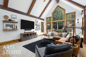 Living area featuring hardwood / wood-style flooring, high vaulted ceiling, beamed ceiling, and healthy amount of natural light