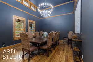 Dining area featuring a high ceiling, hardwood / wood-style floors, a chandelier, and ornamental molding