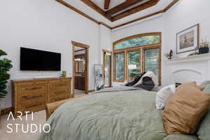 Bedroom featuring a towering ceiling, ensuite bath, light carpet, ornamental molding, and beam ceiling