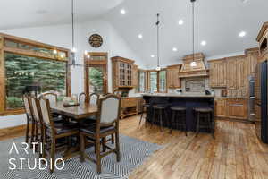 Dining area with a chandelier, light wood-style flooring, high vaulted ceiling, and recessed lighting