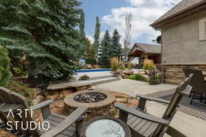 View of patio with a fire pit and an outdoor pool