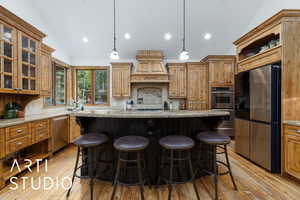 Kitchen featuring glass insert cabinets, backsplash, decorative light fixtures, lofted ceiling, and light stone countertops