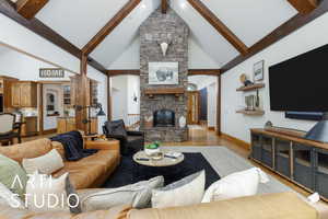 Living area with wood finished floors, high vaulted ceiling, a stone fireplace, beam ceiling, and arched walkways